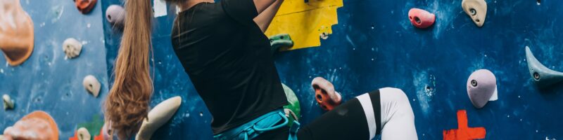 A girl is climbing a bouldering wall.